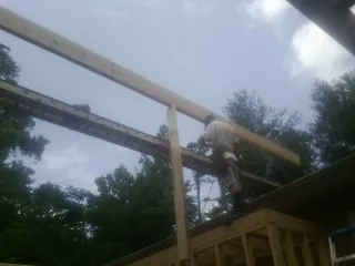 Carpenter setting a ridge beam over a new addition frame — Ice Dam Removal by Roofing Brothers in South Otselic