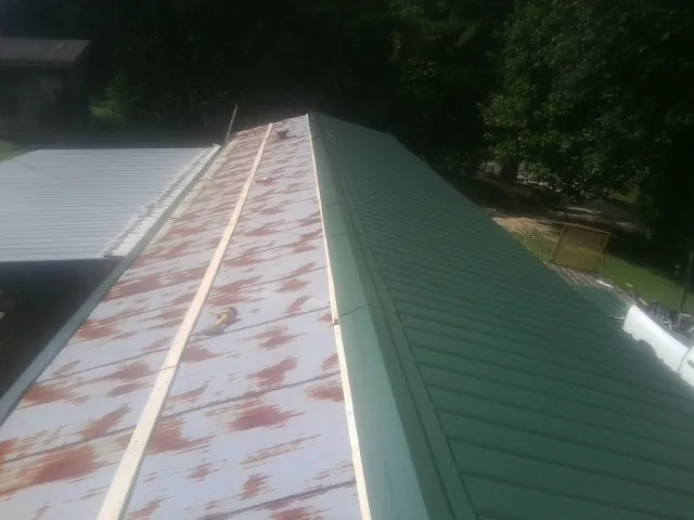 Old rusted panels beside newly installed green metal roofing — Wind Damage Roof Repair by Roofing Brothers in South Otselic