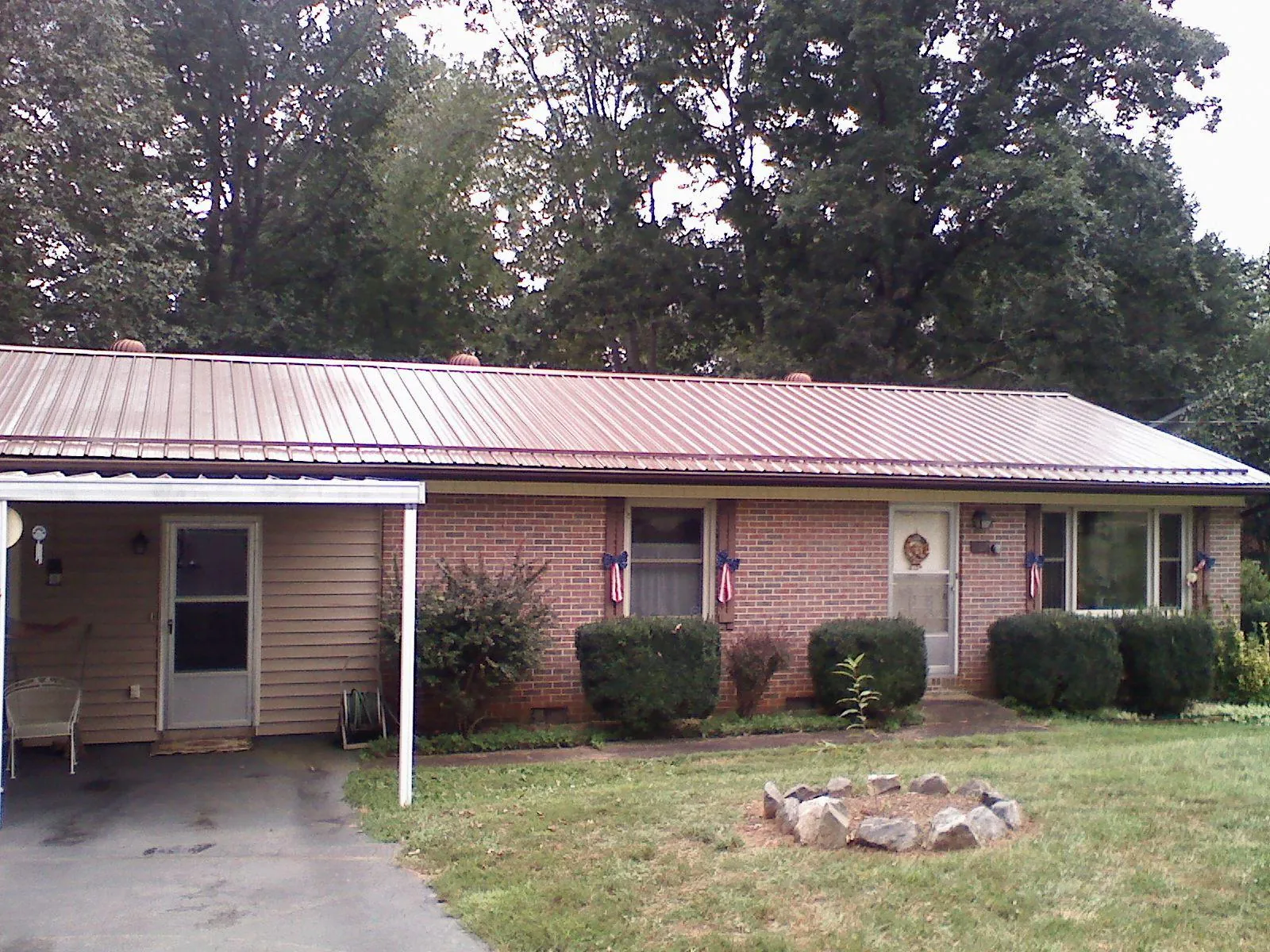 Bronze metal roof and carport on a brick ranch home — Roof Repair work by our crew in South Otselic